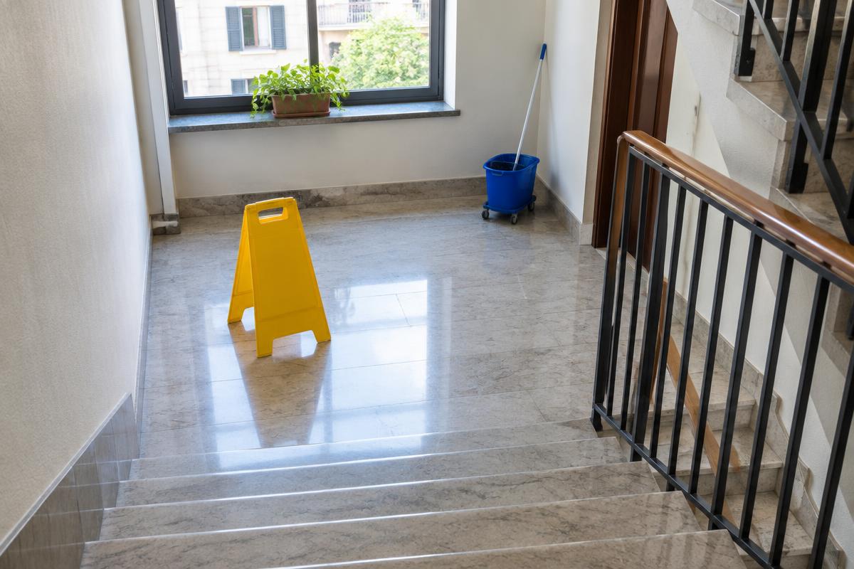 Scale condominiali con attrezzatura di pulizia sul pianerottolo e segnale di pavimento bagnato, immagine illustrativa